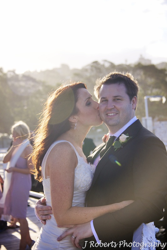 Bride kissing groom with setting sun behind - wedding photography sydney